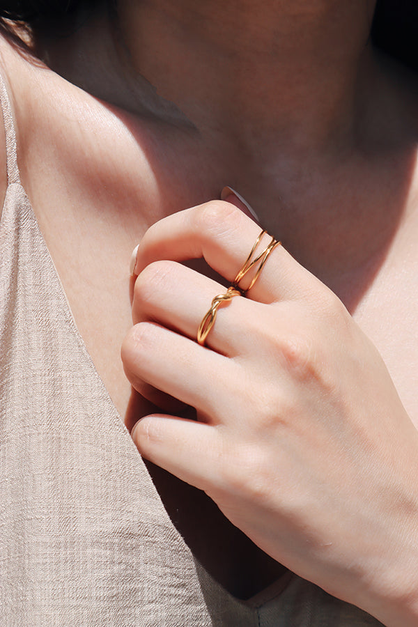 特寫鏡頭展示了模特兒手上佩戴的金色扭結戒指,與另一個簡約線戒搭配,捕捉了時尚且百搭的風格。
