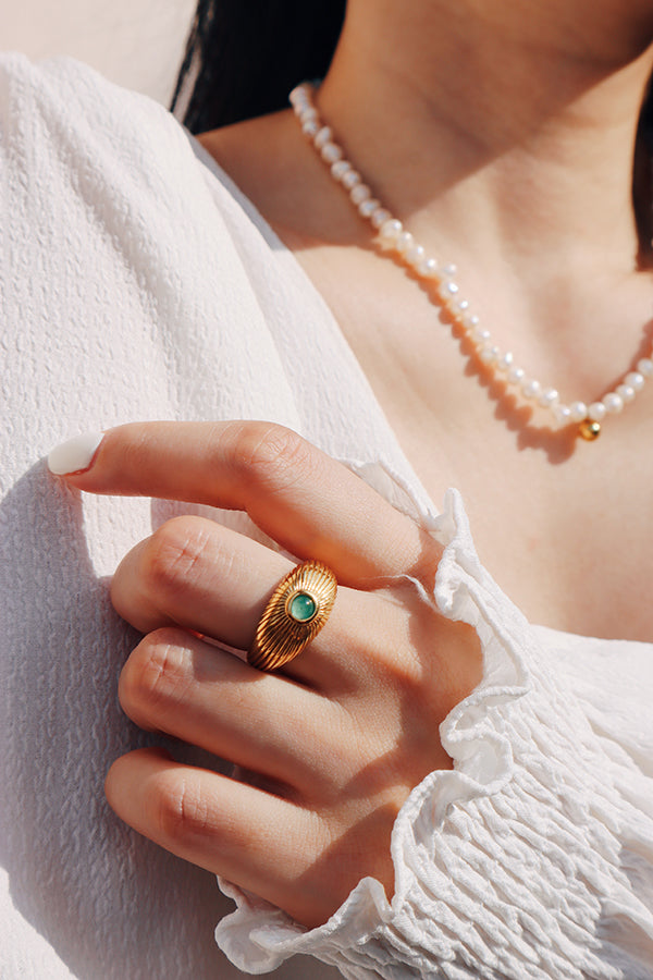 Boho-chic jewelry combination featuring a statement green gemstone ring and a lustrous pearl necklace.