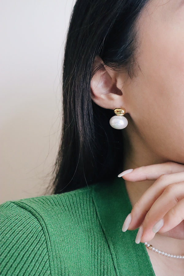 Girl in green top wearing beautiful vintage style pearl stud earrings.