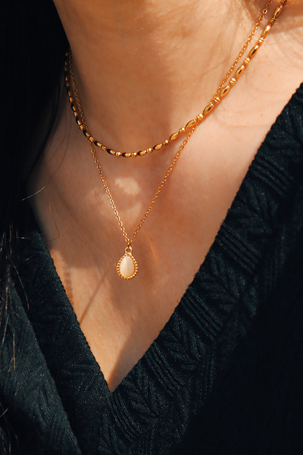 Close-up of a woman wearing a stacked gold necklace set, highlighting the beauty of layering.