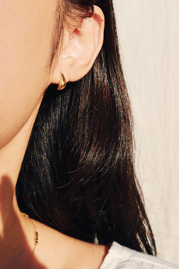 Model showing her cute gold earrings to the camera.