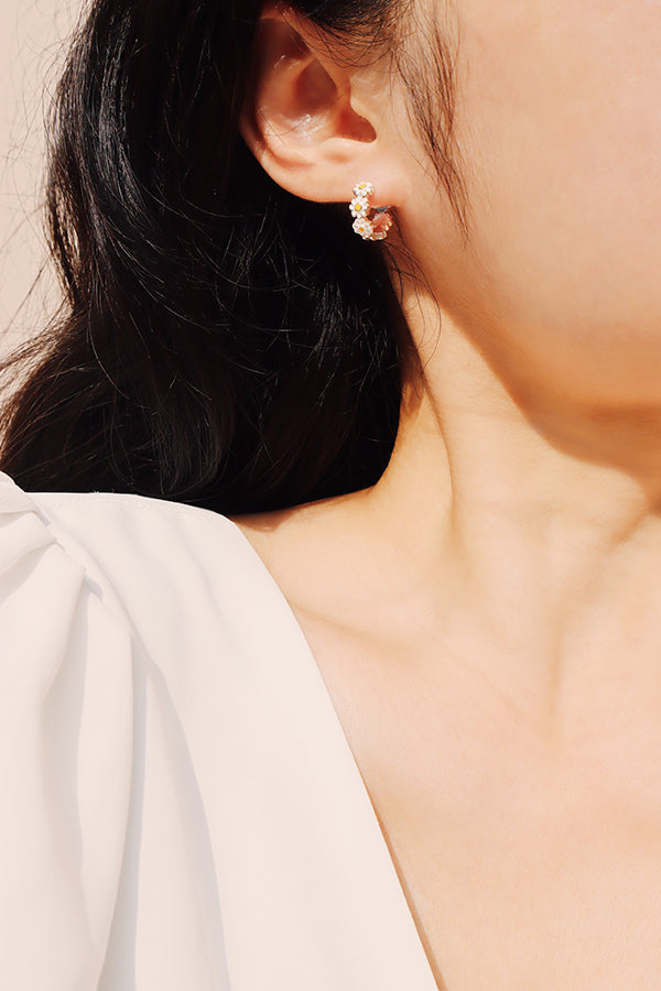 Daisy hoop earrings styled with a simple blouse, adding a sweet floral accent to everyday outfits.