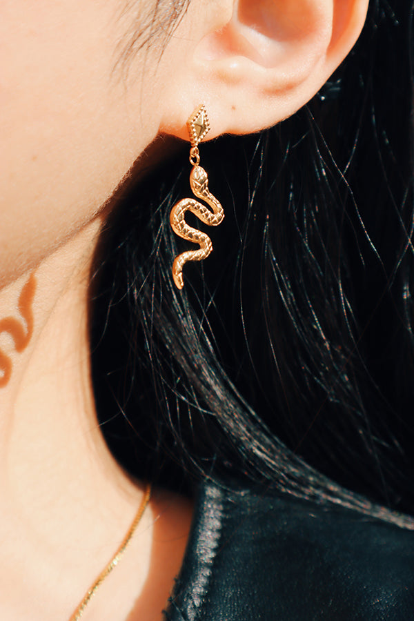 Woman showing her statement snake earring to the camera.