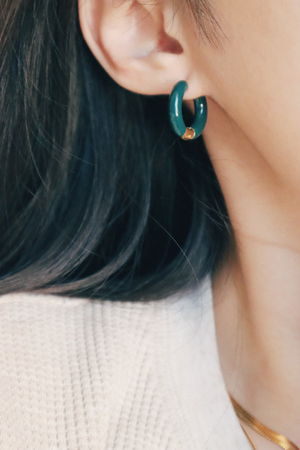Black hair girl in sweater wearing a pair of dark green hoops.