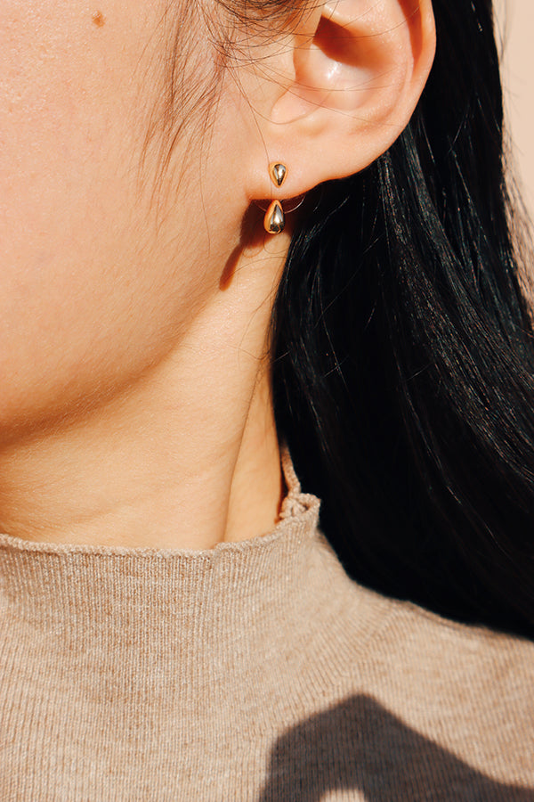 Close-up side view of a model wearing dewdrop duo earrings in gold, styled in the two-way drop formation for a sleek minimalist look.