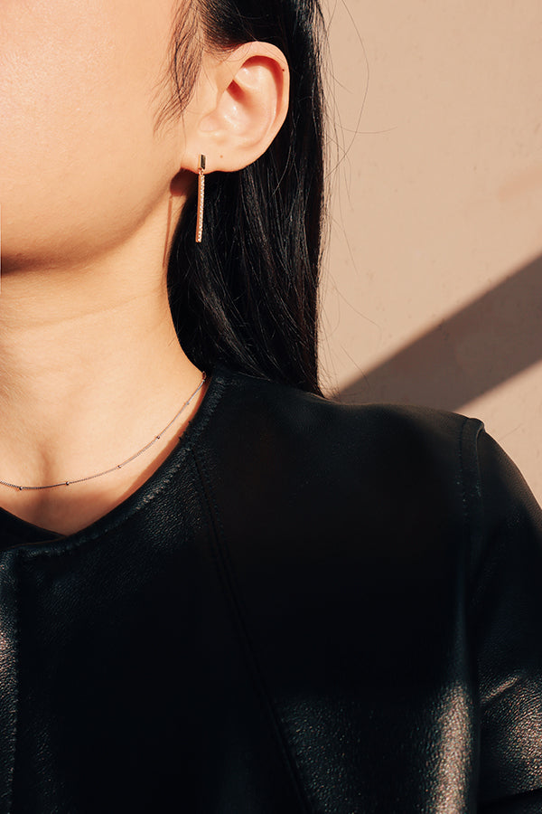 Girl in black standing under the sun and shoing her beautiful necklace and earrings
