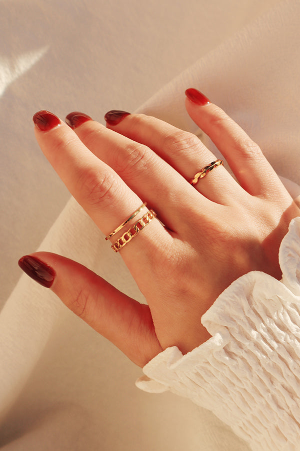 Red nails lady stacking gold rings on her right hand.