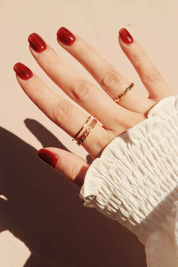 擦了紅色指甲油的女人用兩個不同的金色戒指打造疊戴風格。