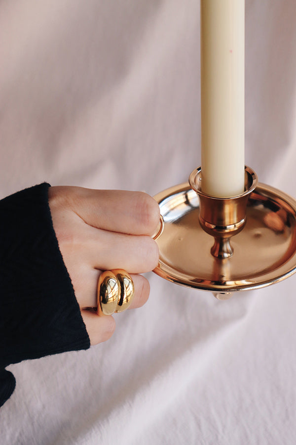 穿黑上衣的女生以帶著寬版金色戒指的手拿蠟燭台。