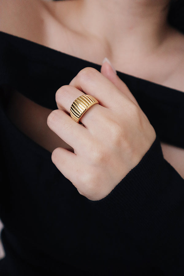 Woman in nightout dress wearing trendy textured gold ring.