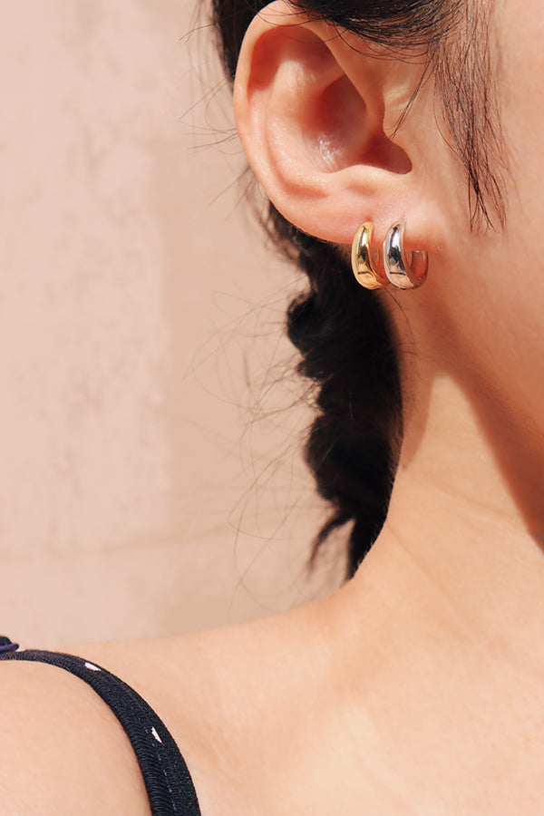 Girl stacking dainty gold and silver huggies under the sun