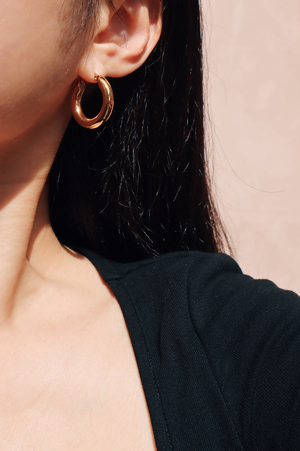 黑髮亞洲時髦女生用金色百搭的經典圈圈耳環點綴自我風格。