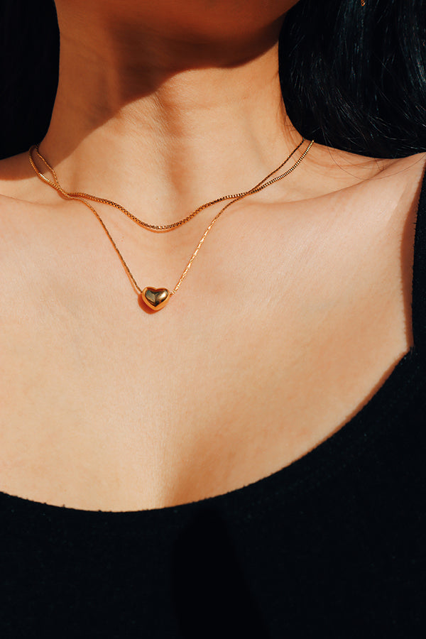 Girl wearing cube chain choker layered with a heart shape necklace under the sun.