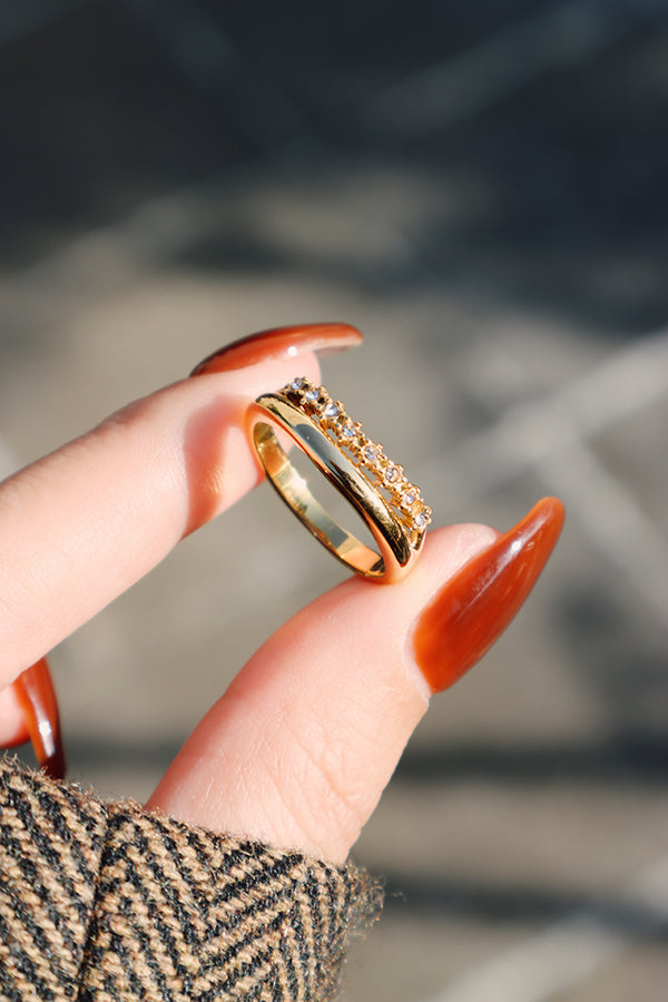 Gold curved zircon stacking ring held between fingers, slim profile ideal for stacking or solo wear.