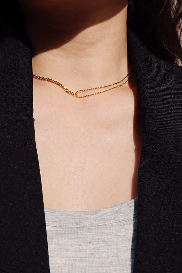 Gold double layer chain necklace resting along the collarbone, featuring clean lines and a sleek modern silhouette.