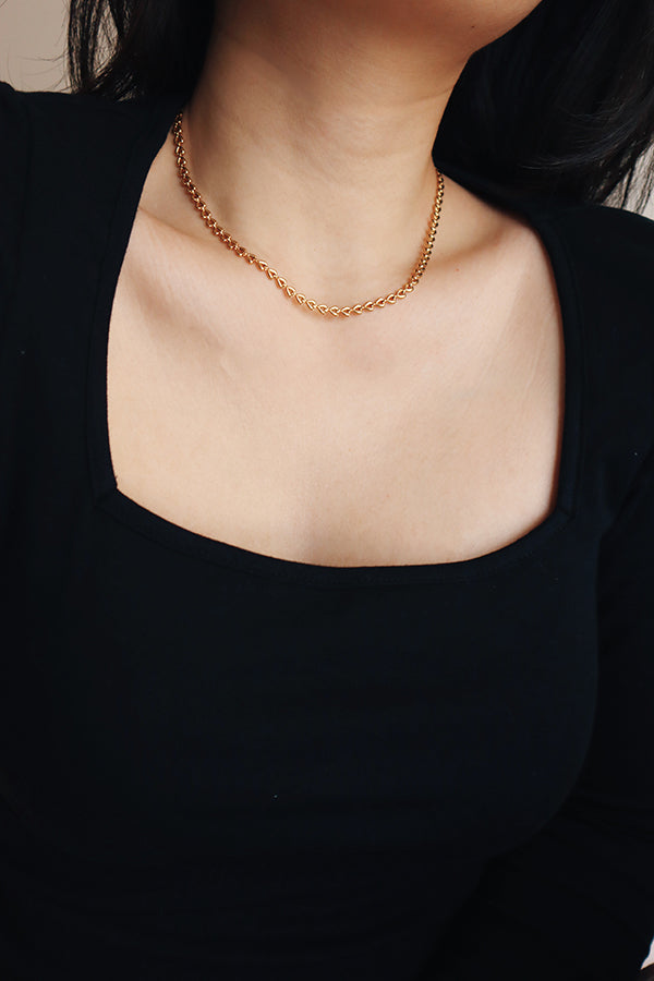 Woman wearing trendy gold heart chain necklace for date night.