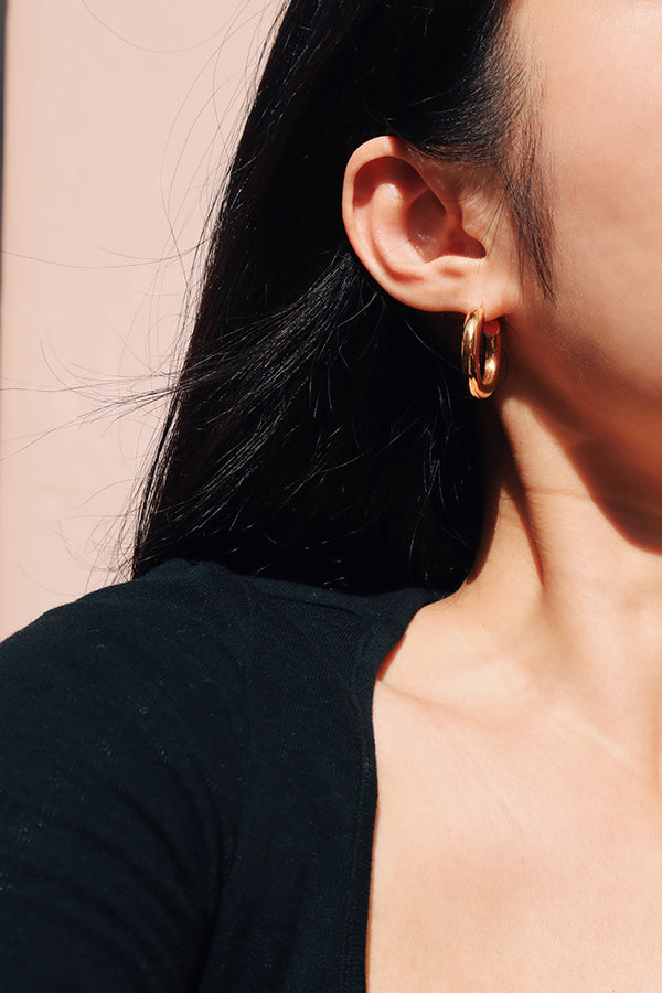 Girl in black showing her gold hoops under the sun.