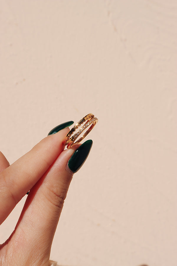 模特兒手上拿著一枚金色雙層纖細戒指,向鏡頭展示精緻細節和優雅風格。