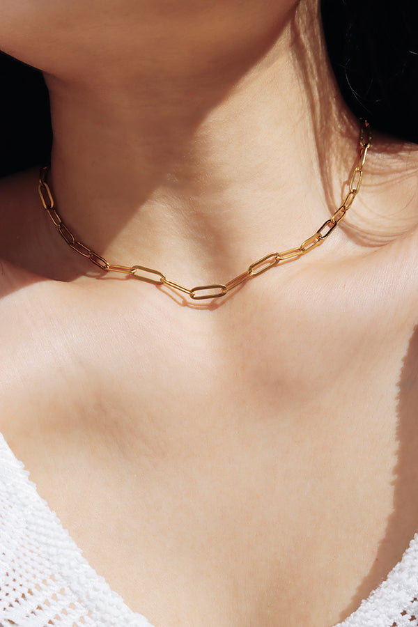 Gold paperclip chain necklace reflecting natural sunlight with a subtle modern shine.