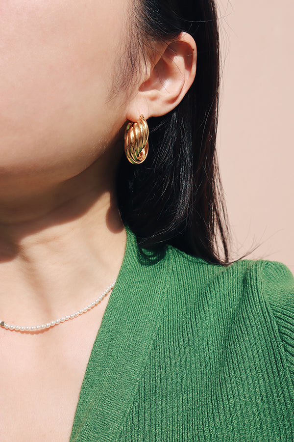 Girl wearing gold shell like hoops with shnco's slim pearl necklace under the sun