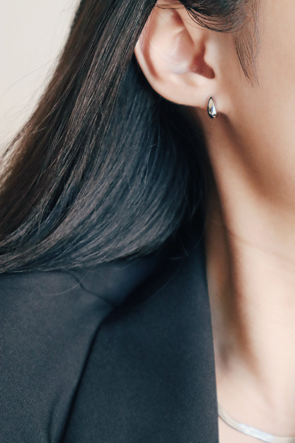 穿黑色套裝的上班族女性配戴小巧精緻的銀色日常耳環。