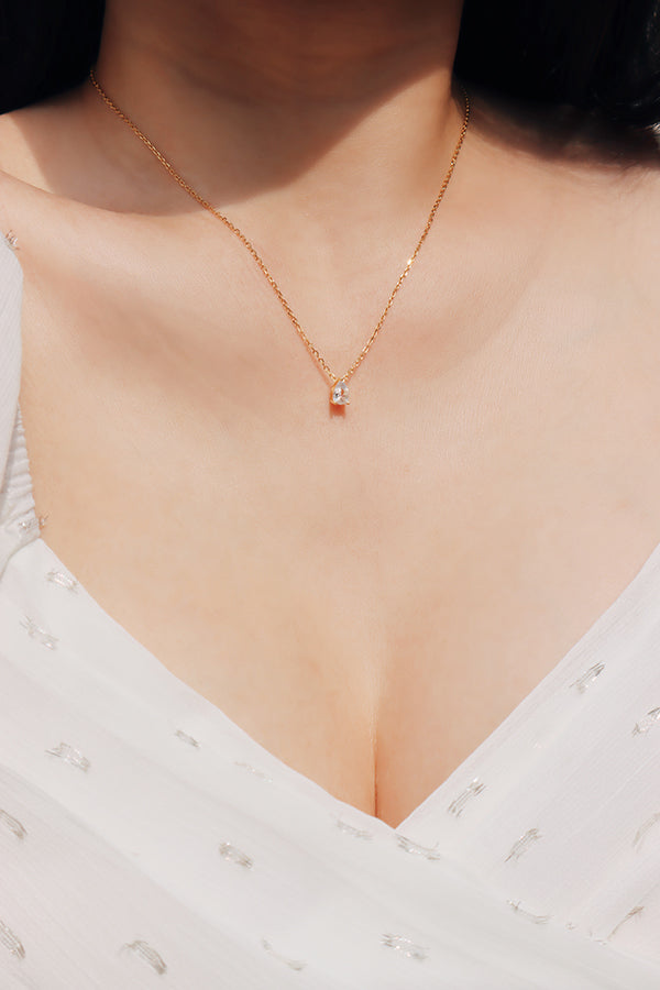 Woman in white dress wearing shiny drop necklace