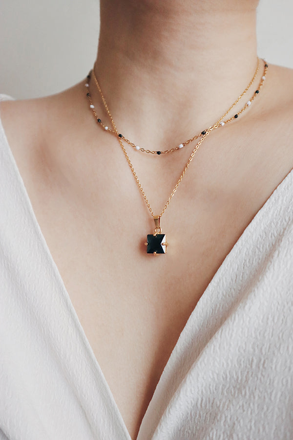 Woman layering 2 necklaces for her date dress.