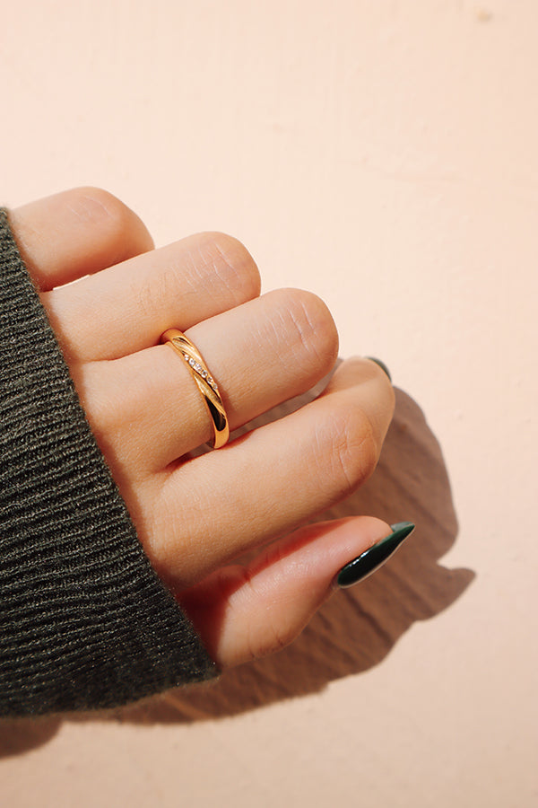 一枚金色的刻紋鋯石戒指戴在手指上,搭配綠色毛衣,營造出溫暖且時尚的造型。