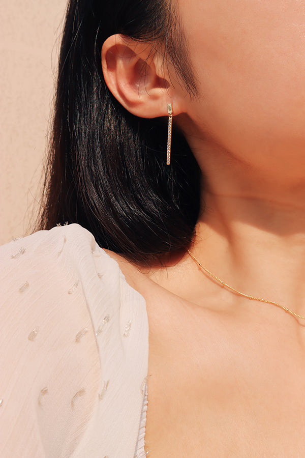 Black hair model wearing dainty sparkling drop earrings.