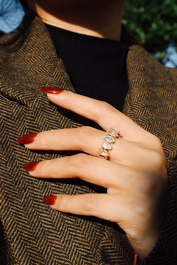 Gold marquise crystal ring styled with a black turtleneck and brown blazer for a refined everyday outfit.