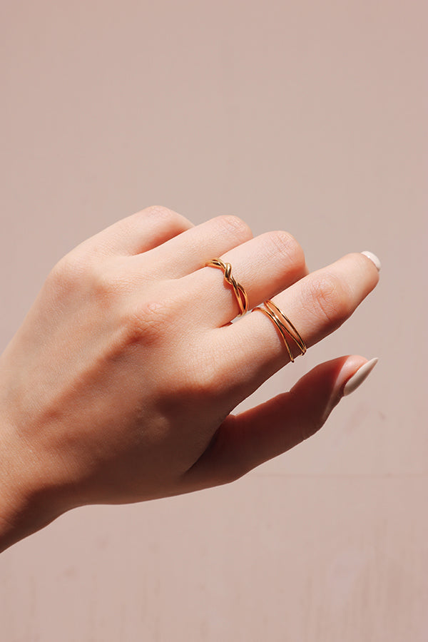 手部特寫展示了女性疊戴的金色戒指,展現出簡潔而高雅的美感。