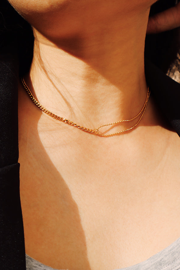 金色雙層短鍊在光影下展現俐落線條,適合極簡穿搭。