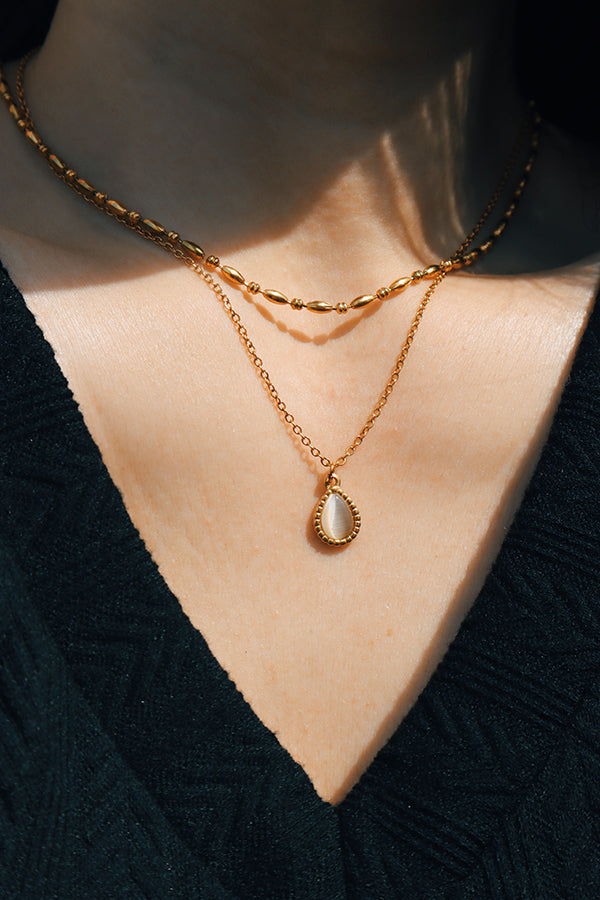 Minimalist gold layering featuring a beaded necklace and a dainty gold chain with a cat eye drop.