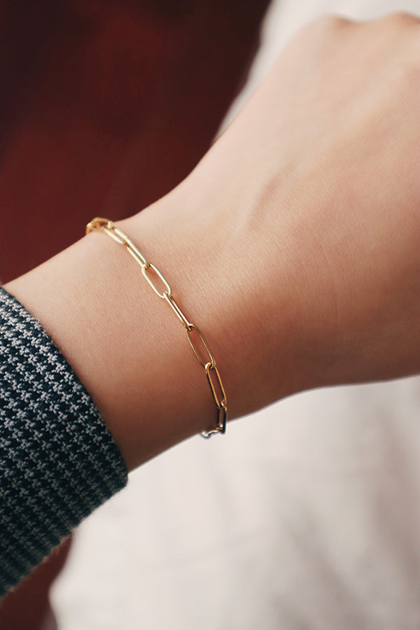 Woman in suit showing her dainty gold bracelet to the camera
