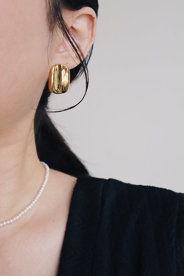 Woman in black dress wearing pearl choker and bold earrings for night outfit