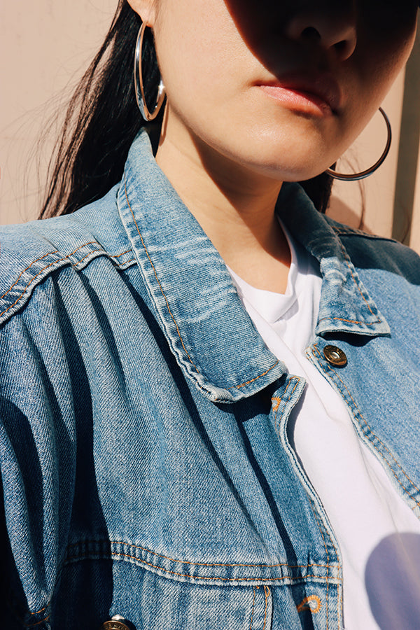 Woman wearing large hoops, bold silver stainless steel hoop earrings styled with a denim jacket for an edgy look.