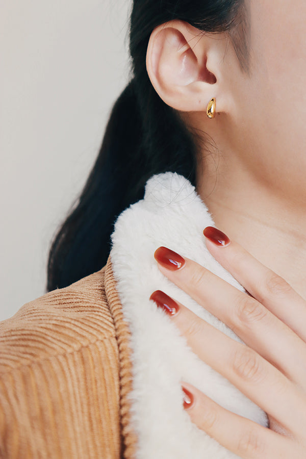 Black hair girl wearing trendy gold dome stud earrings for winter fashion.