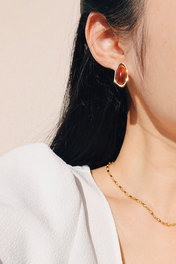 Amber color gold earrings styled with a white blouse, showcasing refined styling and natural luster.