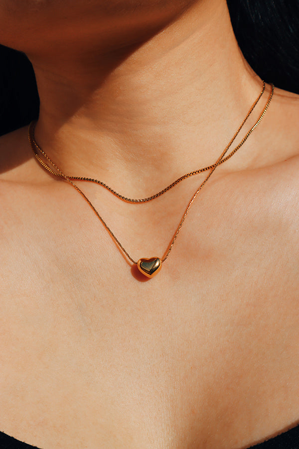 Girl wearing aria heart charm gold necklace from shnco showing collar bone.