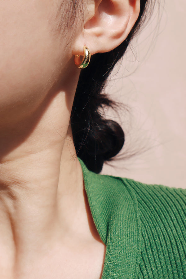 Girl wearing green cardigan with a small gold huggies under the sun
