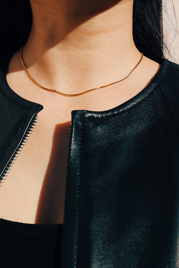 Black leather jacket girl wearing gold cube chain choker under the sun