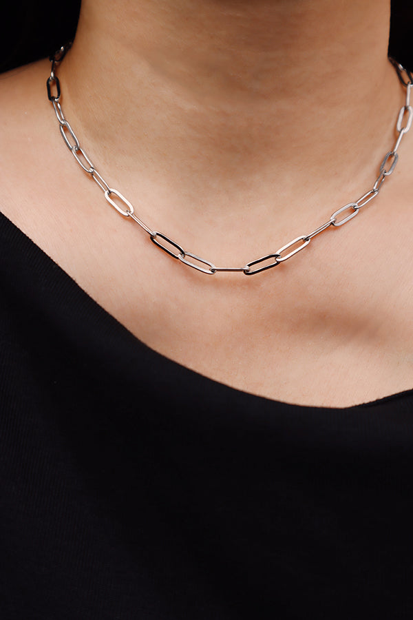 Silver paperclip chain necklace worn alone with a black top for a clean minimalist style.