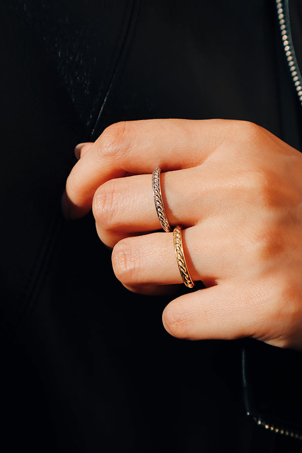 Model in black stacks two tone color rings on fingers