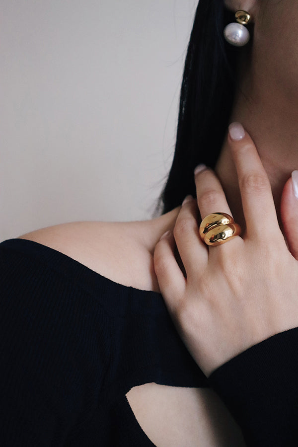 穿黑色洋裝的優雅模特兒配戴著復古珍珠耳環及份量感圓弧金戒指。