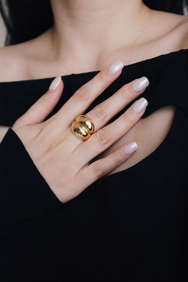 Woman in black dress wearing bold chunky gold ring for night.