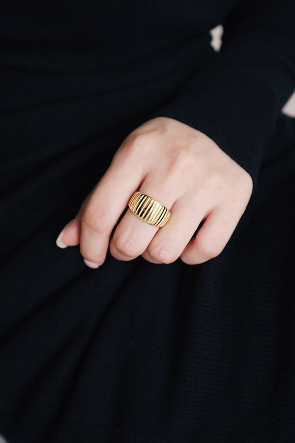 黑色洋裝的女性左手中指配戴金色時尚寬面戒指作為派對穿搭。