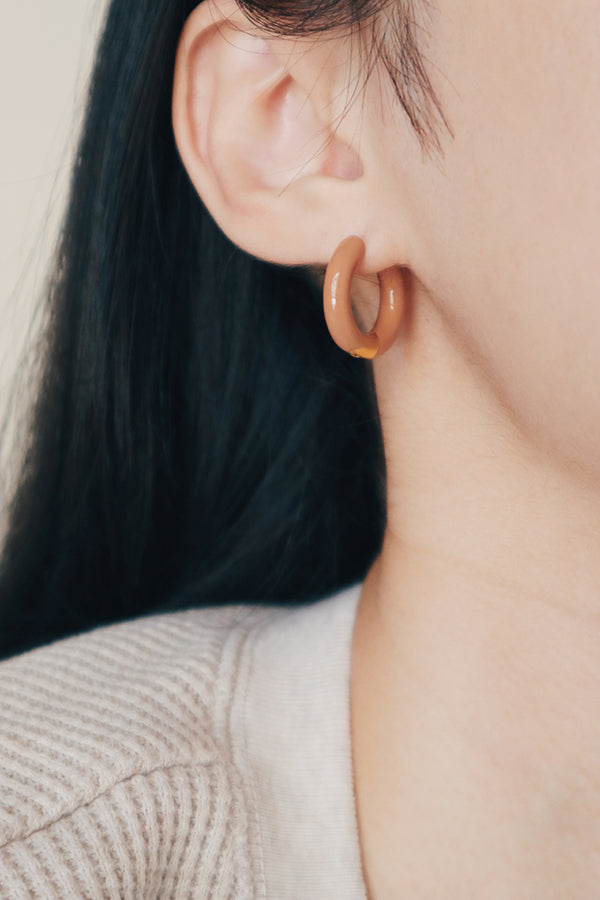 Model showing her morandi color earrings to camera.