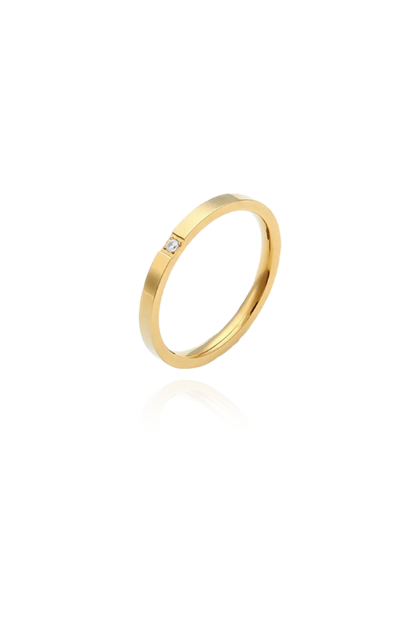 A product image of a thin gold ring featuring a single cubic zirconia stone. The ring is displayed flat, highlighting its minimalist design and versatility for stacking or wearing as a simple, understated piece.