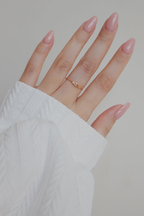 A close-up of a hand wearing three dainty gold stacking rings, with twisted and slender bands.