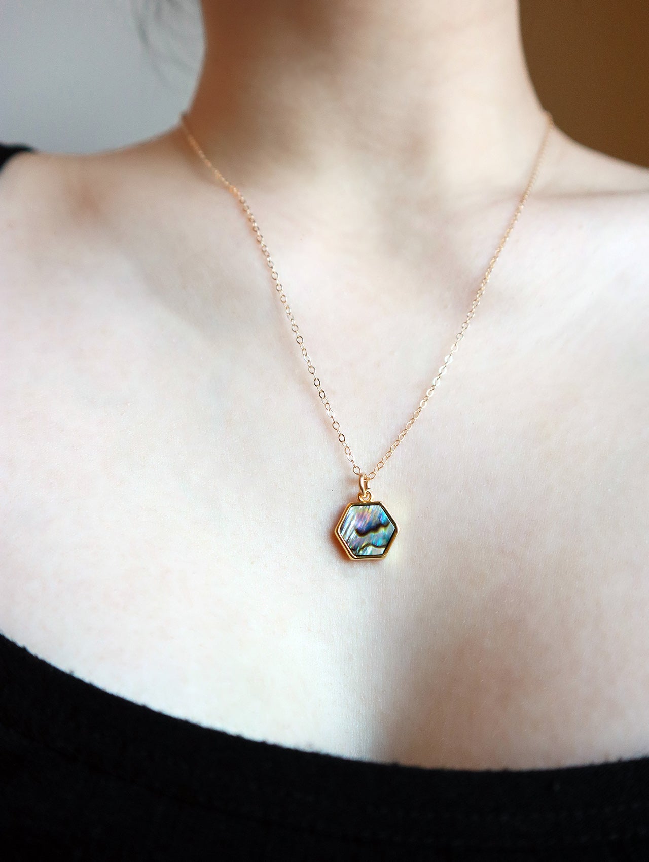 Woman in black top wearing colorful abalone necklace